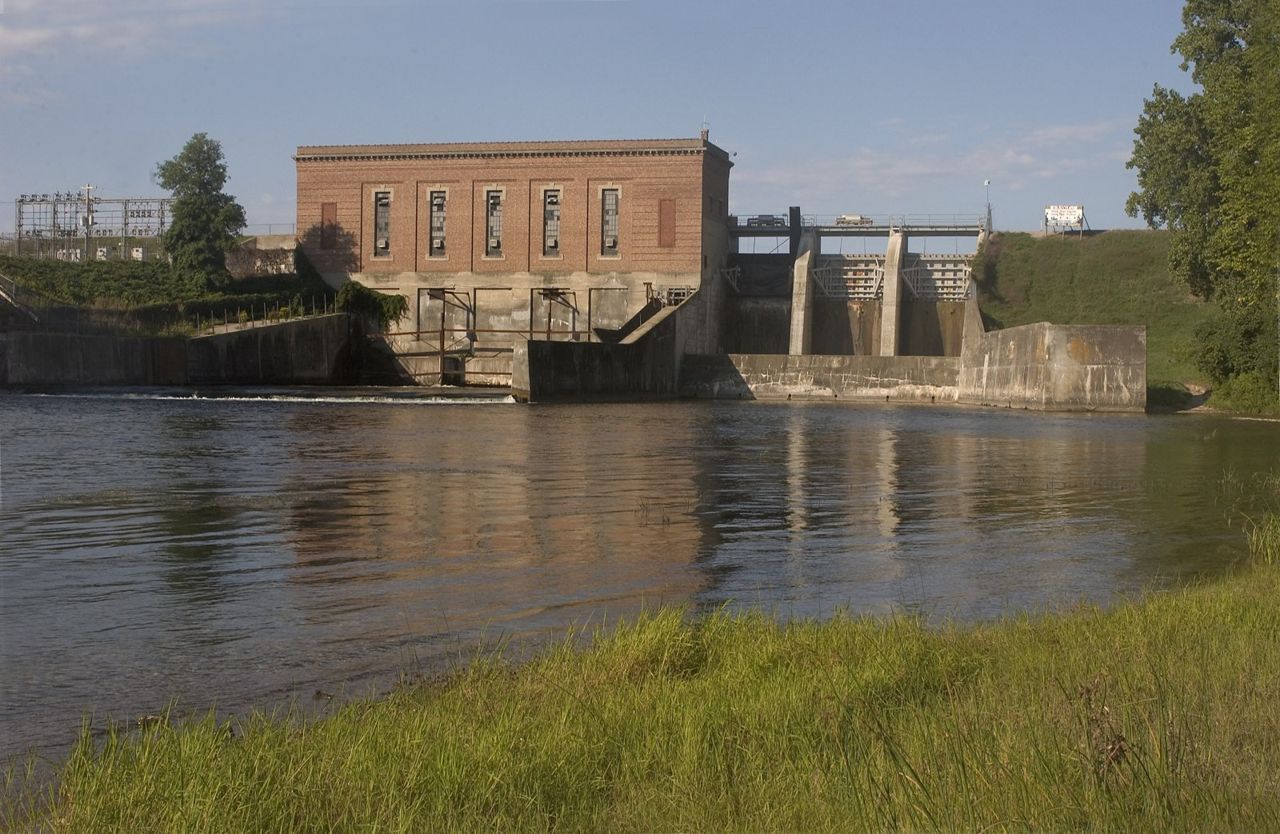 A weathered hydroelectric building associated with Foote Dam operations stands in the distance. The dam is on the AuSable River on the River Road Scenic Byway.