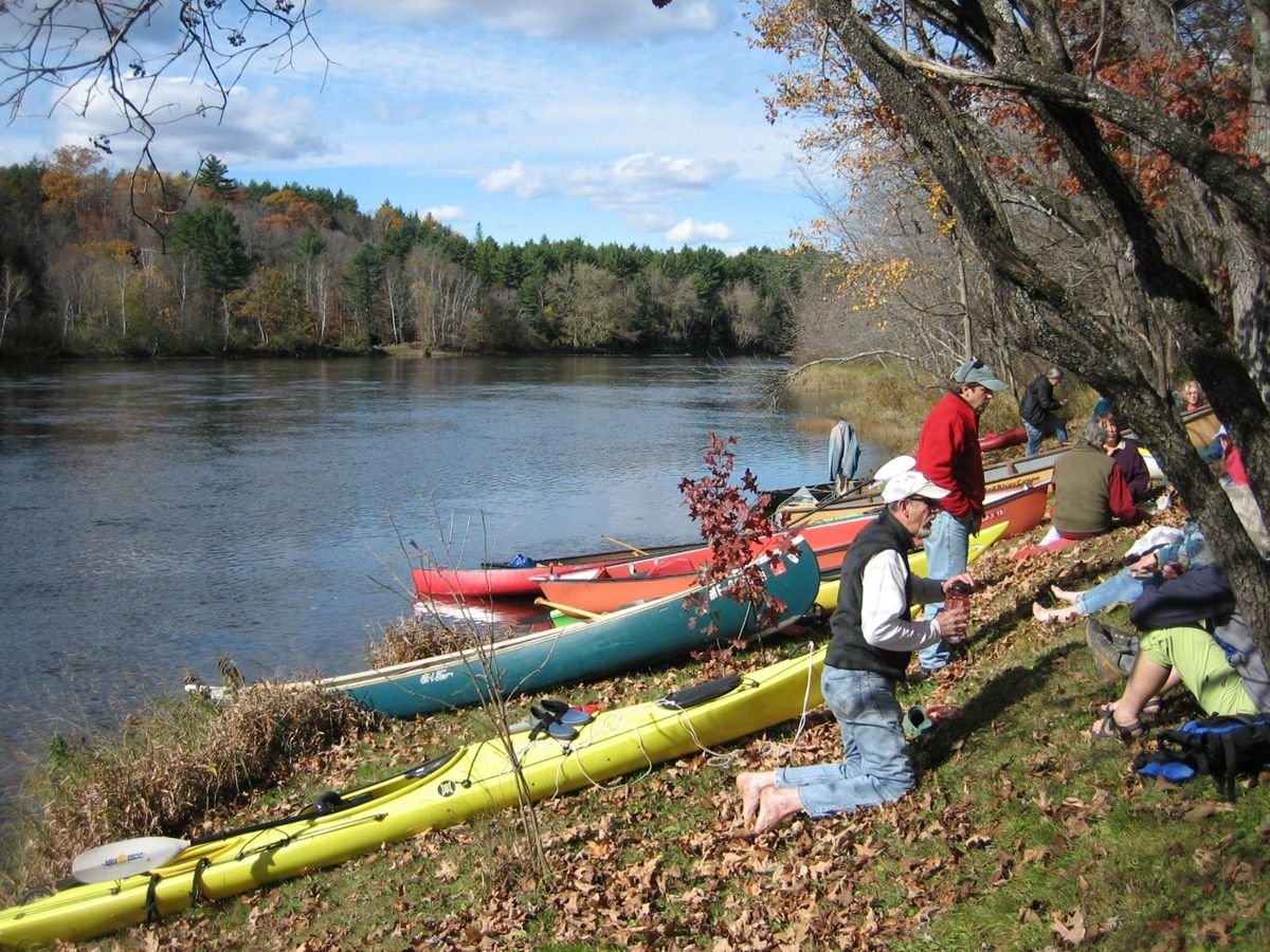 Some canoers socialize and prepare to go canoeing on the Kennebec River.