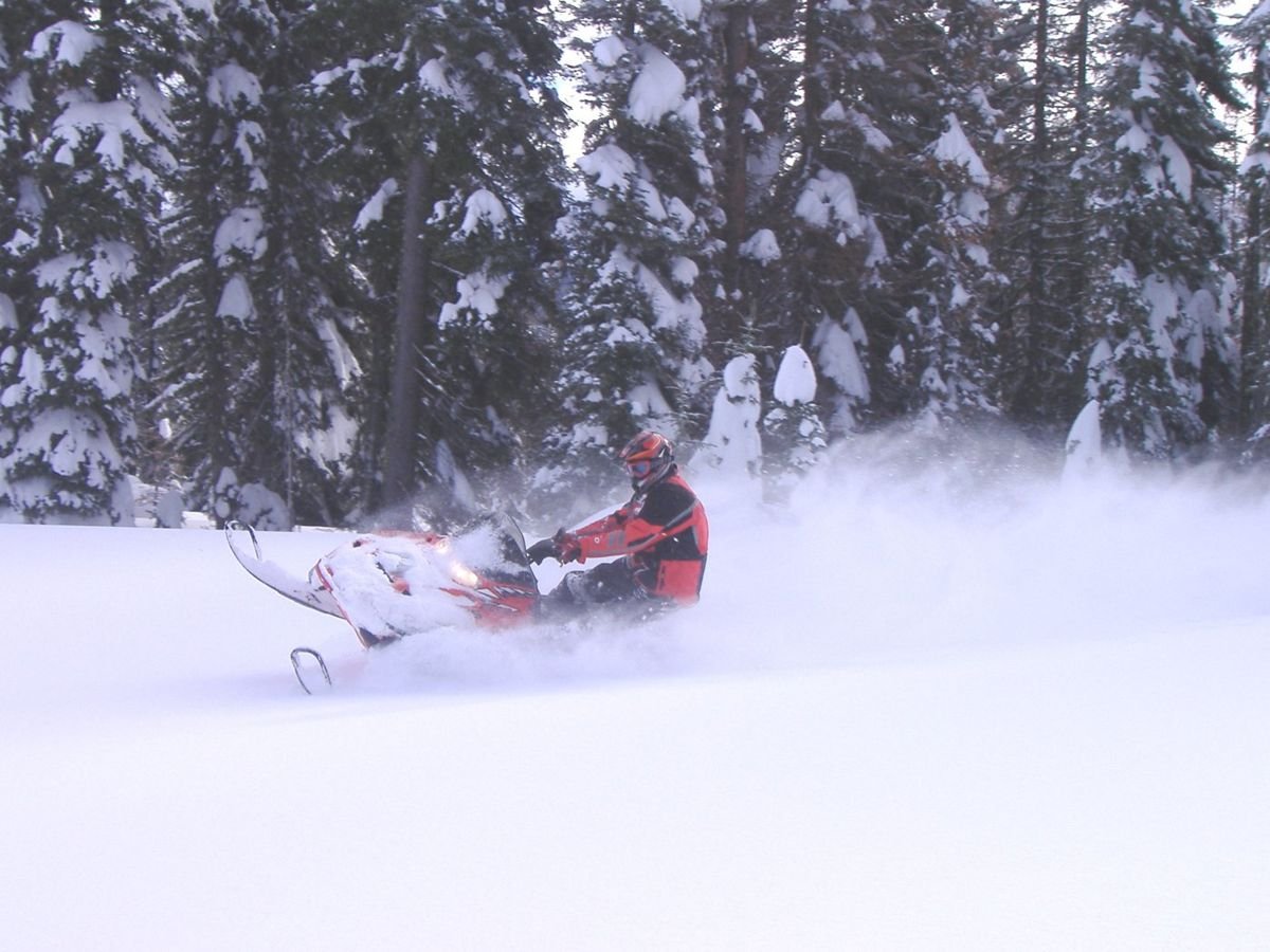 A snowmobiler maneuvers at high speed through deep powder near Hells Canyon Scenic Byway.